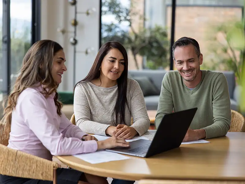 business person going through options with man and woman on laptop