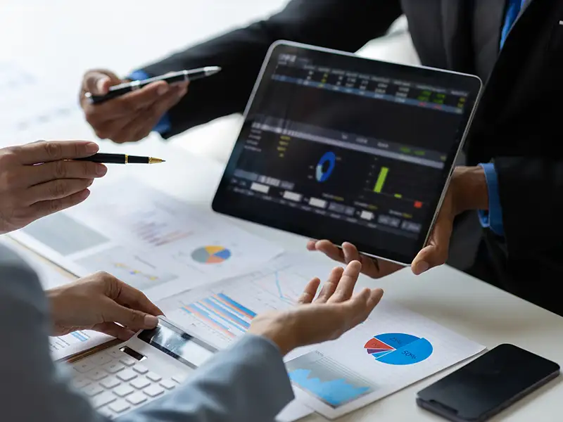 business people pointing to data on tablet screen on office desk