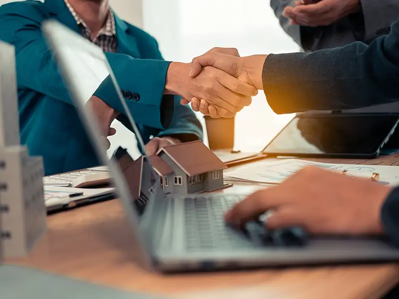 business people shaking hands in front of laptop on desk