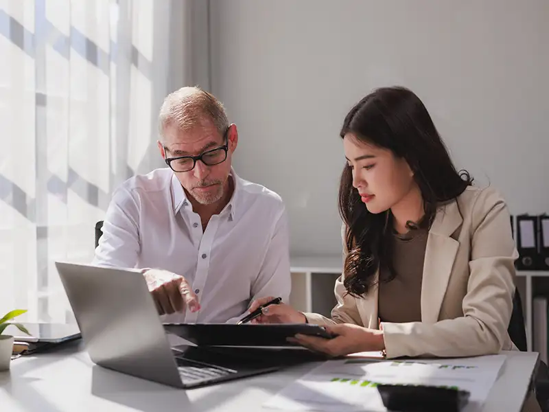 man and woman looking at data on laptop together in office