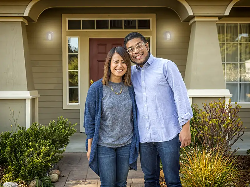 man and woman smiling together in front of the porch at home