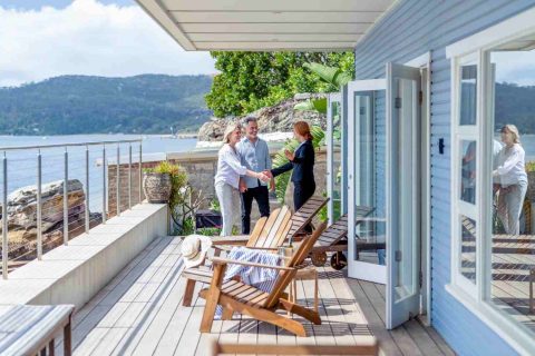 Property owners discussing rental property management outside a waterfront home